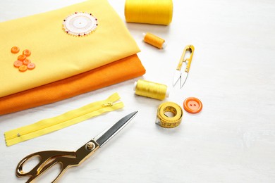 Photo of Different sewing supplies and fabric on white table