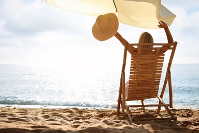 Photo of Woman relaxing on deck chair at sandy beach. Summer vacation
