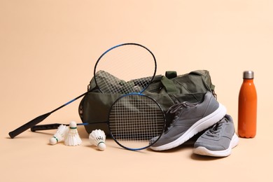 Photo of Badminton set, bag, sneakers and bottle on beige background