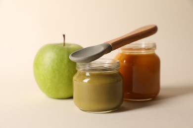 Photo of Healthy baby food, apple and spoon on beige background