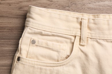 Photo of Stylish beige  jeans on wooden background, closeup of inset pocket