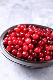 Fresh ripe cranberries in bowl on grey table, closeup