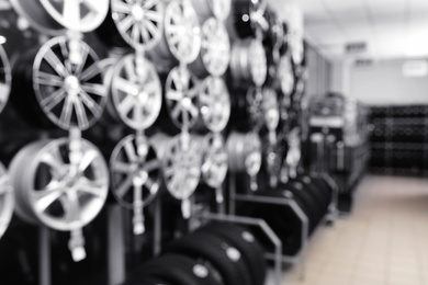 Photo of Blurred view of car tires and alloy wheels on rack in auto store