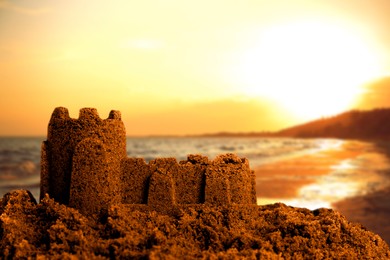 Image of Sand castle on ocean beach at sunset, closeup with space for text. Outdoor play