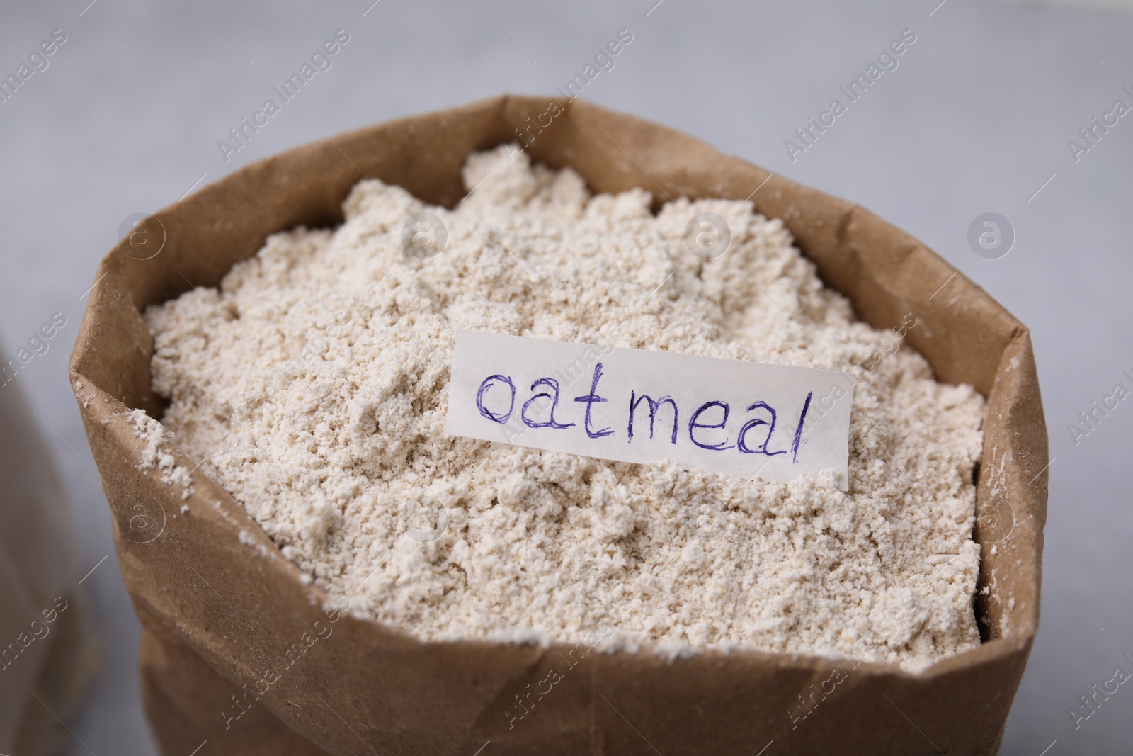 Photo of Sack with oatmeal flour on light table, closeup