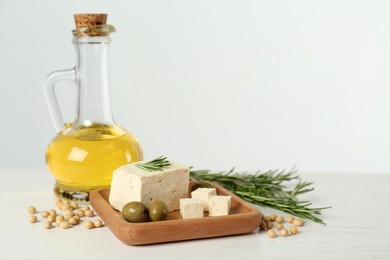 Pieces of delicious tofu with rosemary, olives and soy on white table, space for text