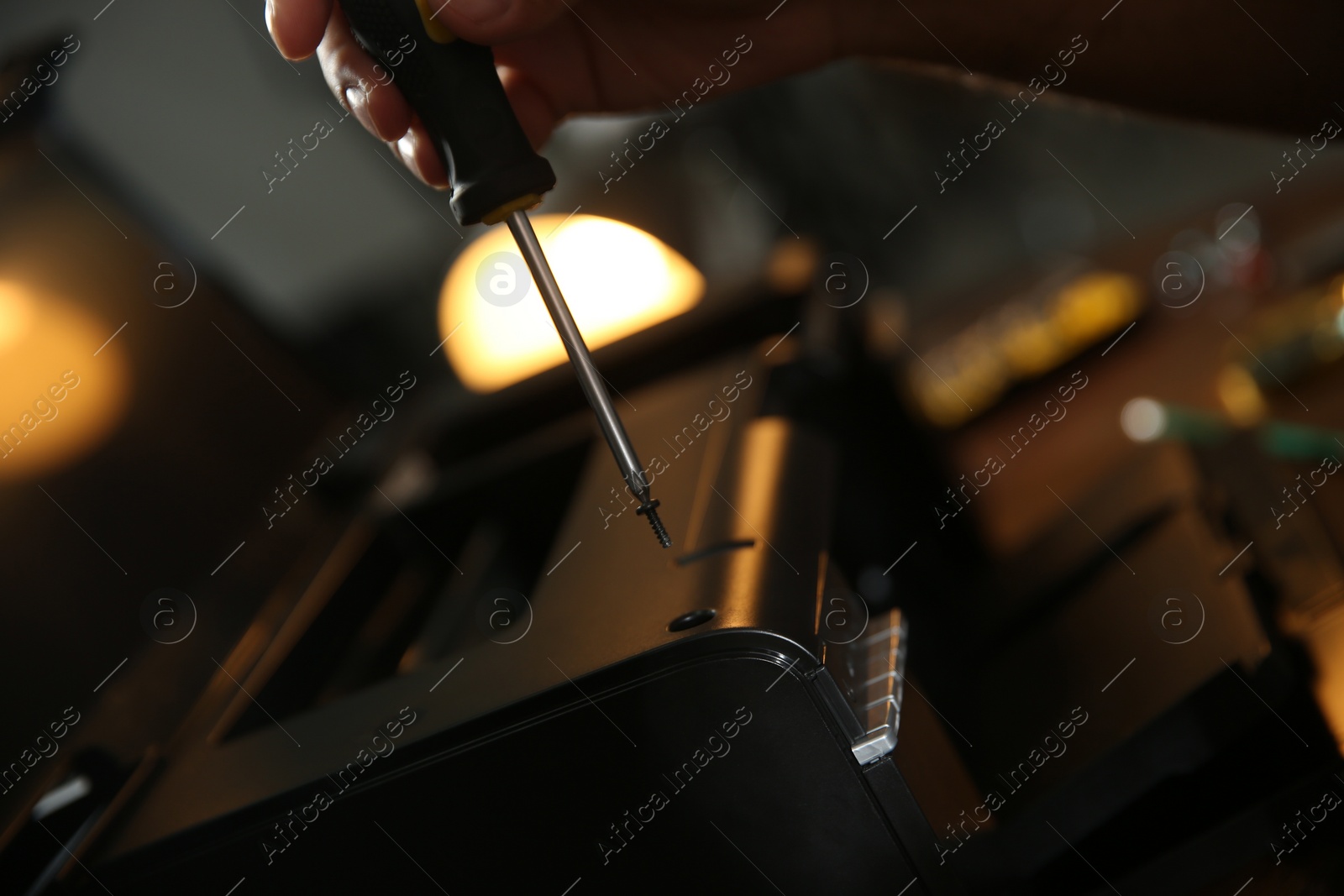 Photo of Repairman with screwdriver fixing modern printer, closeup