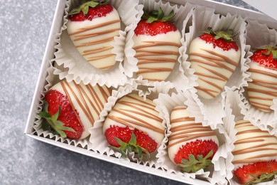 Box with delicious chocolate covered strawberries on light grey table, top view