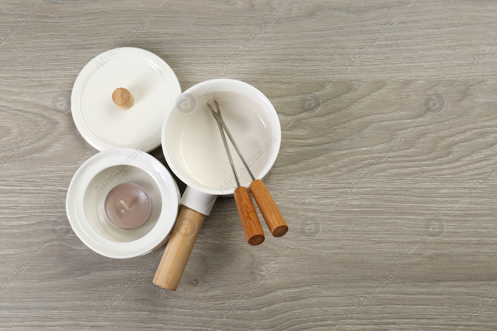 Photo of Fondue set on wooden table, flat lay. Space for text