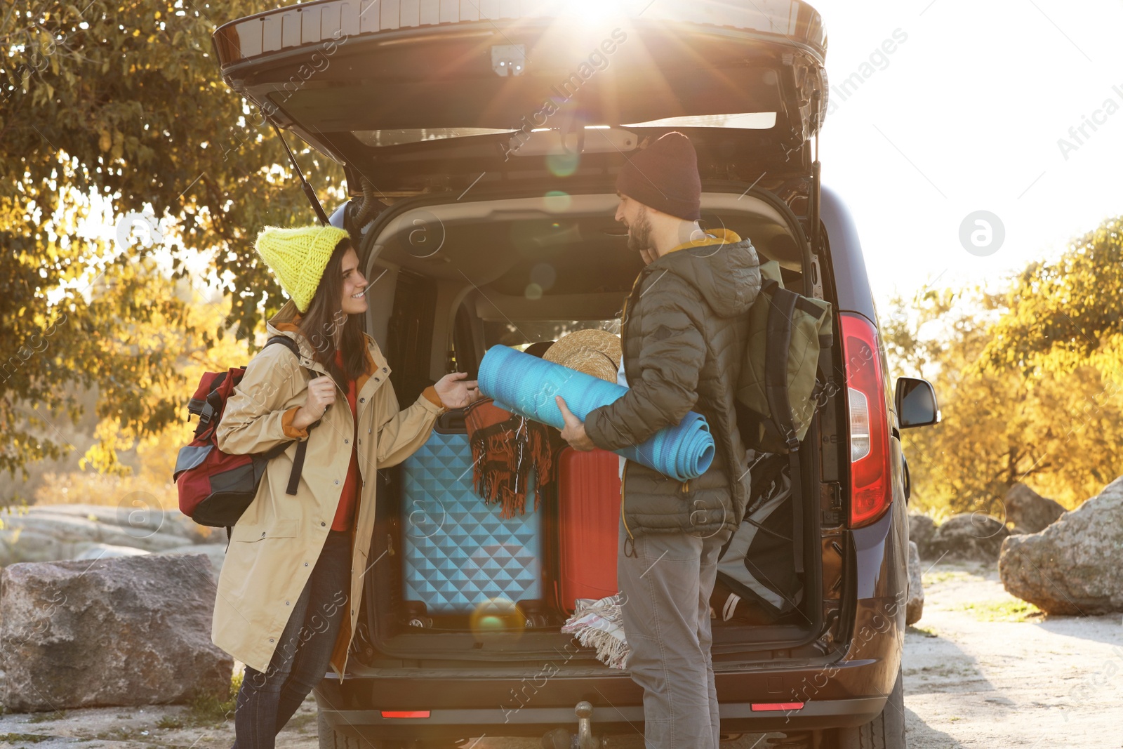 Photo of Young couple with camping equipment near car trunk outdoors