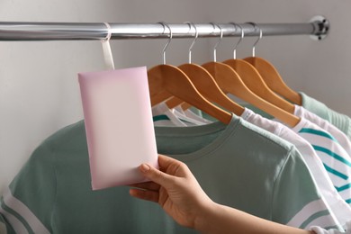 Photo of Woman holding scented sachet in wardrobe, closeup