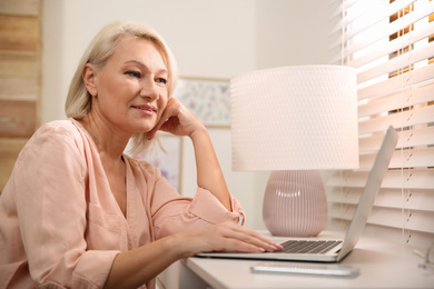 Beautiful mature woman working with laptop at home