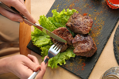 Woman eating tasty shish kebab in cafe