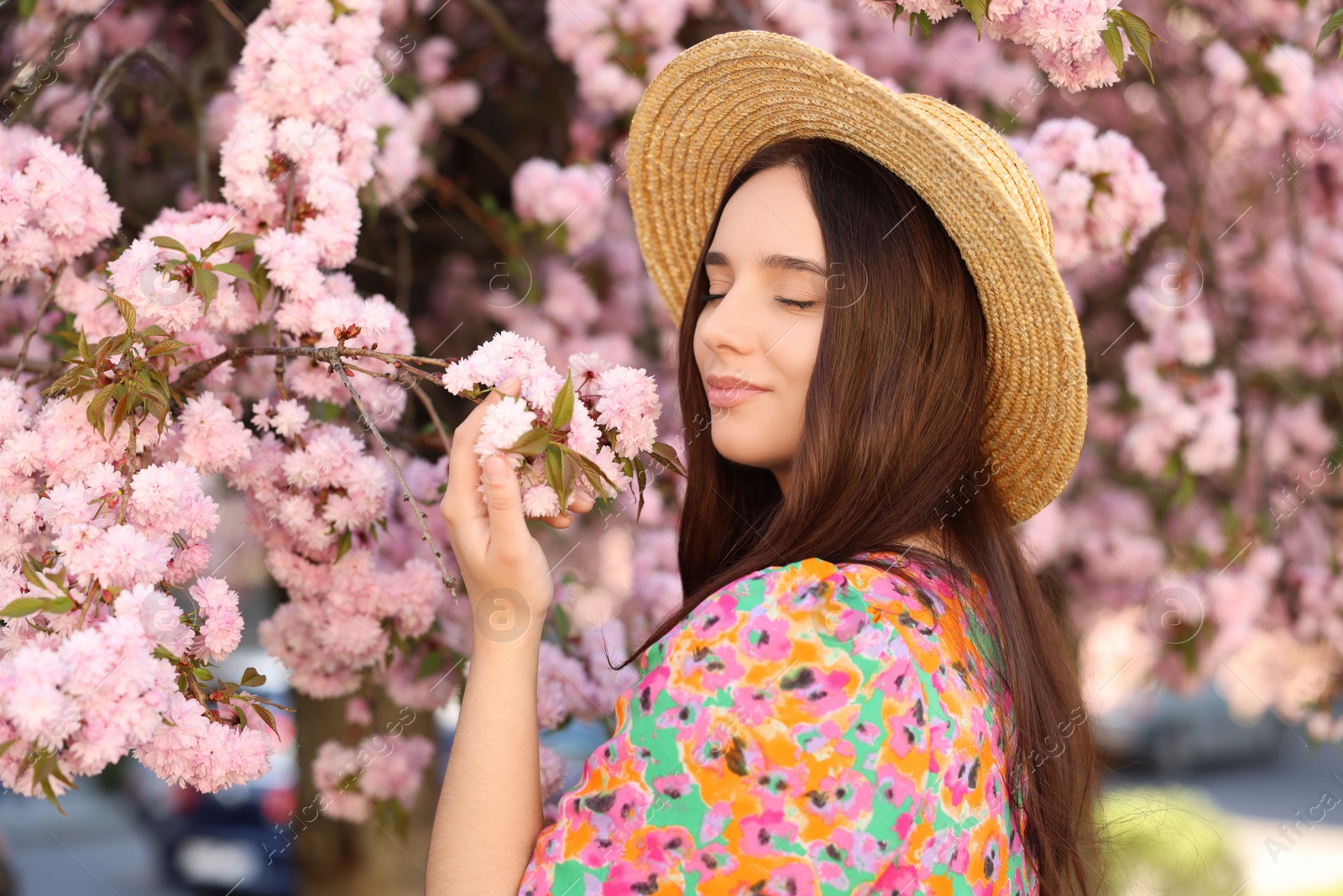 Photo of Beautiful woman in straw hat near blossoming tree on spring day