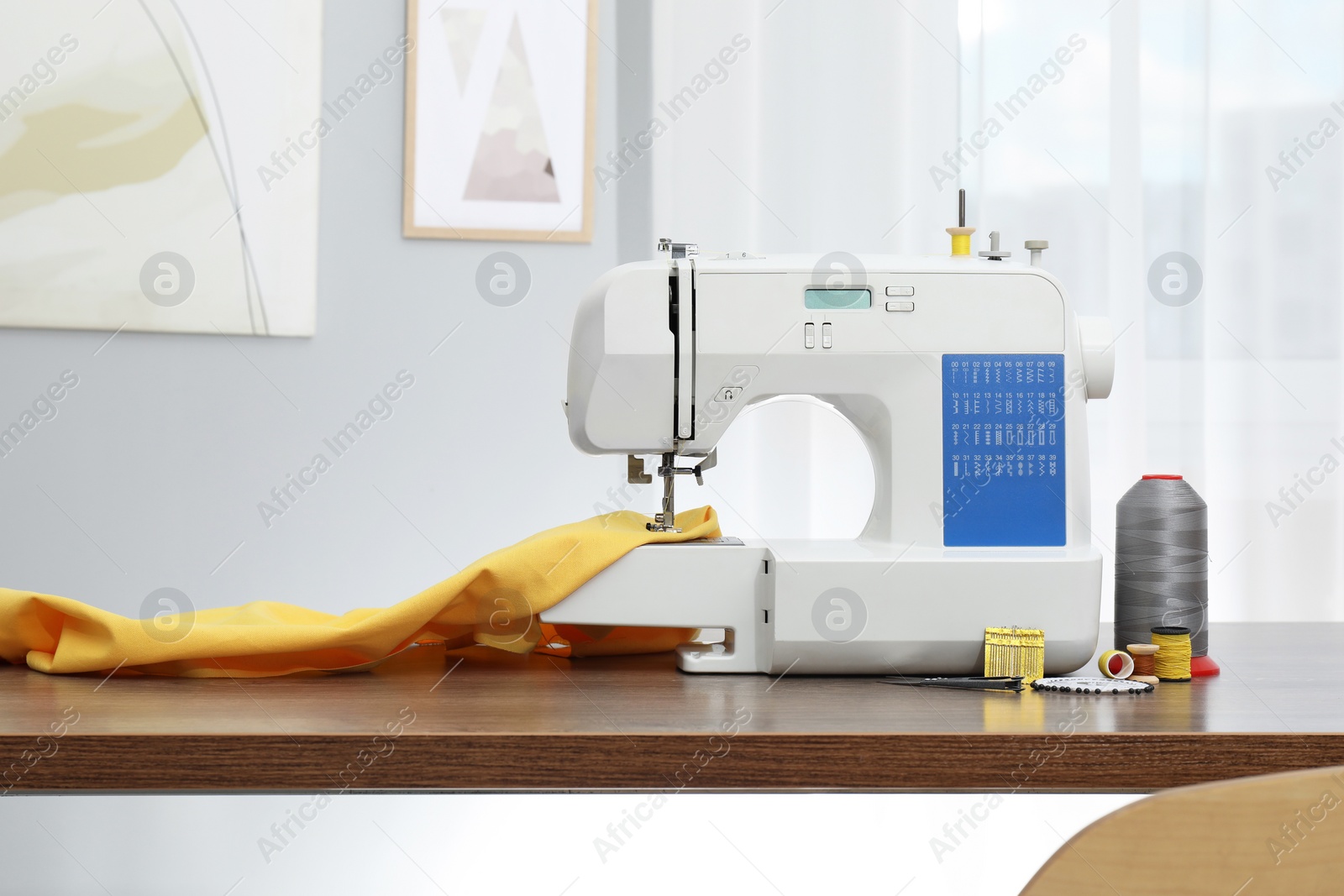 Photo of Sewing machine with fabric and craft accessories on wooden table indoors