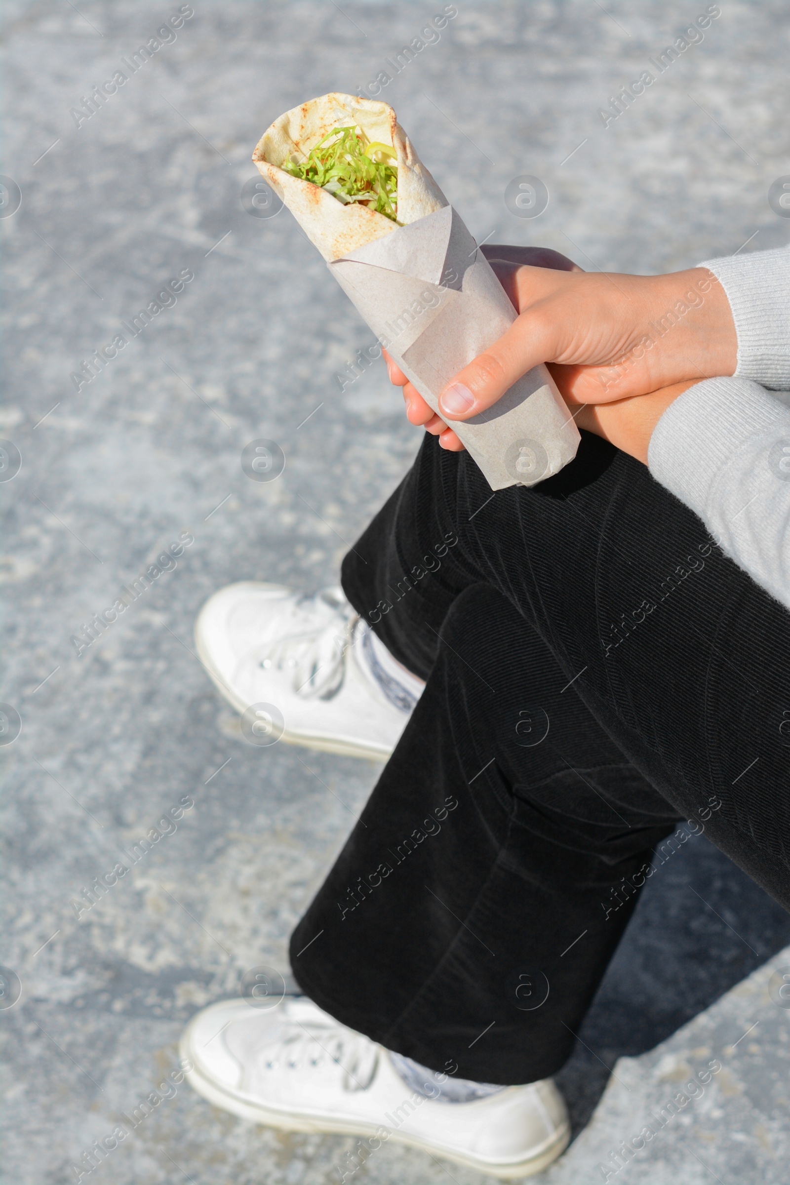 Photo of Woman holding delicious vegetable roll outdoors, closeup