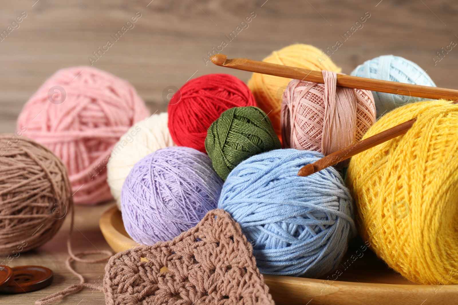 Photo of Many different clews of colorful knitting threads and crochet hooks on wooden table