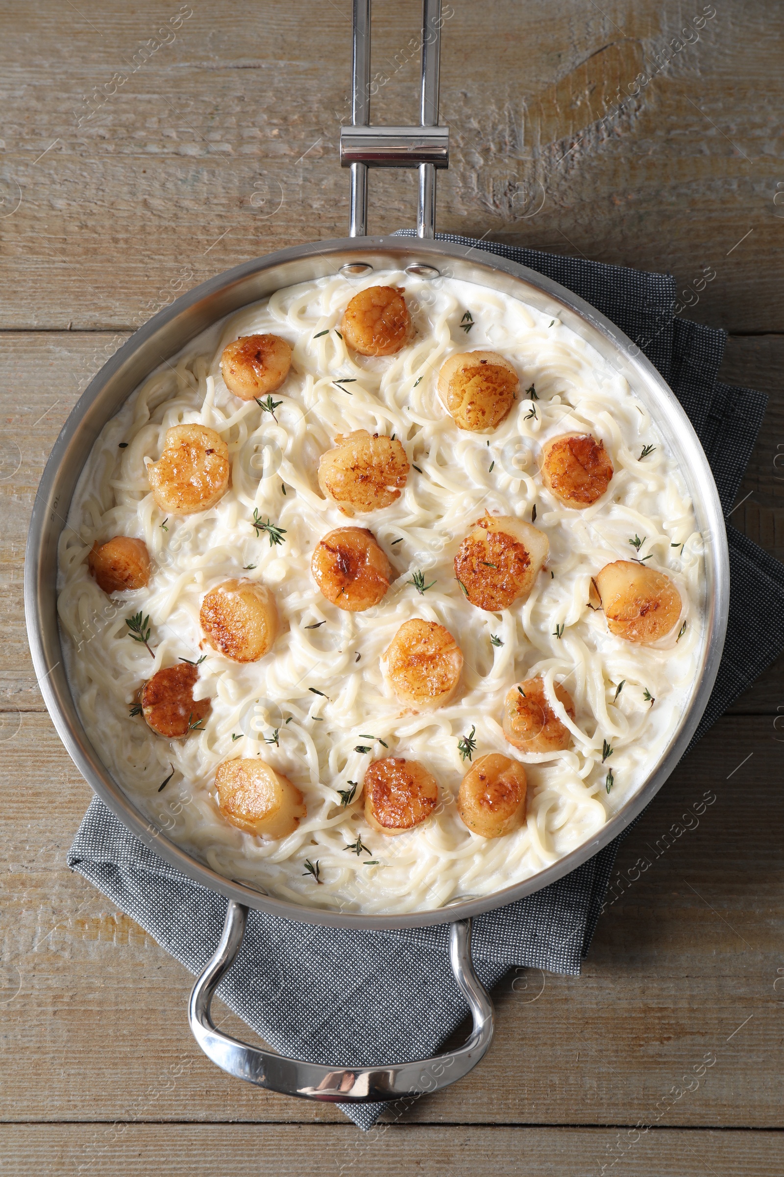 Photo of Delicious scallop pasta in pan on wooden table, top view