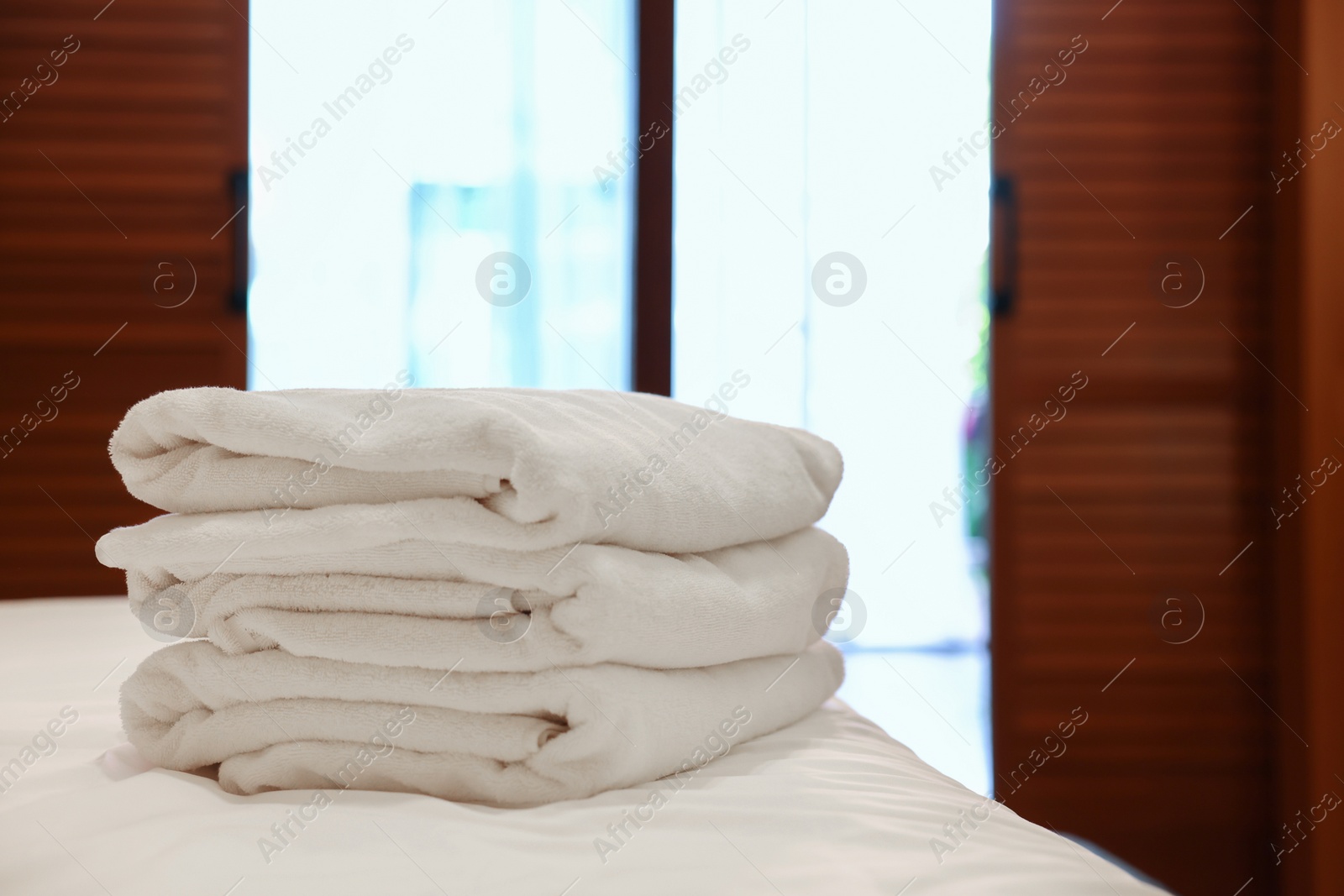 Photo of Stacked towels on bed in hotel room, space for text