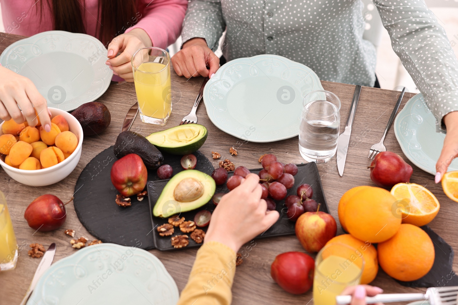 Photo of Friends eating vegetarian food at wooden table indoors, closeup