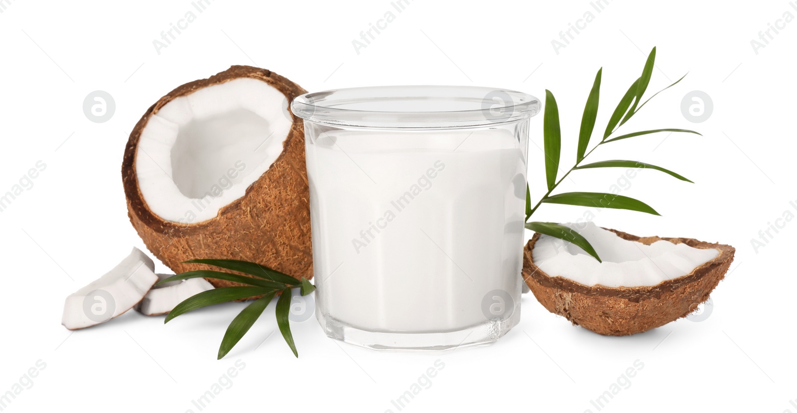 Photo of Glass of delicious vegan milk, coconut pieces and green leaves on white background