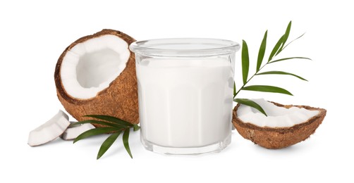 Photo of Glass of delicious vegan milk, coconut pieces and green leaves on white background