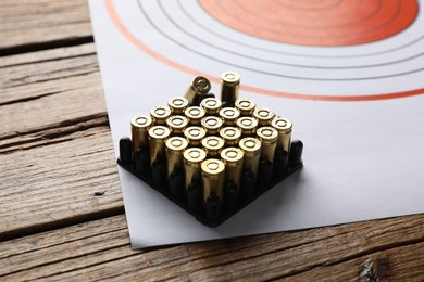 Photo of Shooting target and bullets on wooden table, closeup