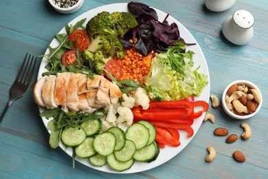 Photo of Balanced diet and healthy foods. Plate with different delicious products on light blue wooden table, flat lay