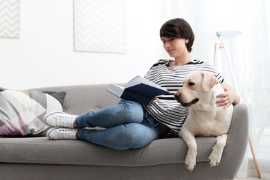 Photo of Adorable yellow labrador retriever with owner on couch indoors