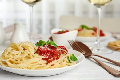 Tasty pasta with basil and tomato sauce on white wooden table, closeup