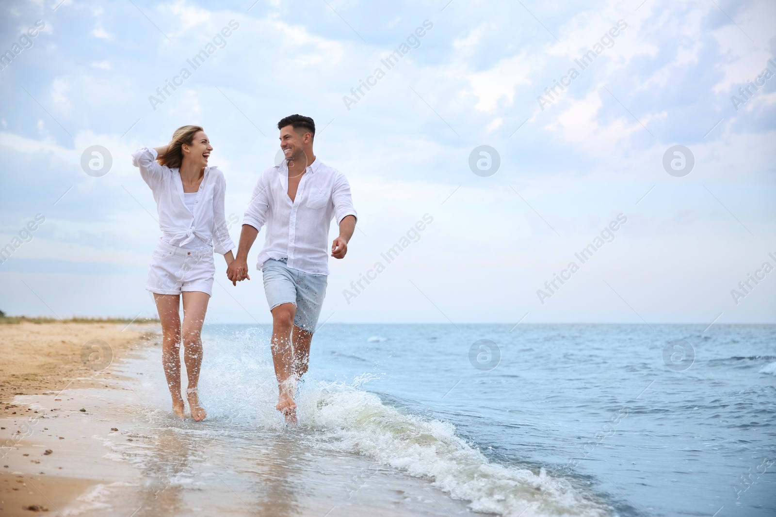 Photo of Happy couple having romantic walk on beach. Space for text