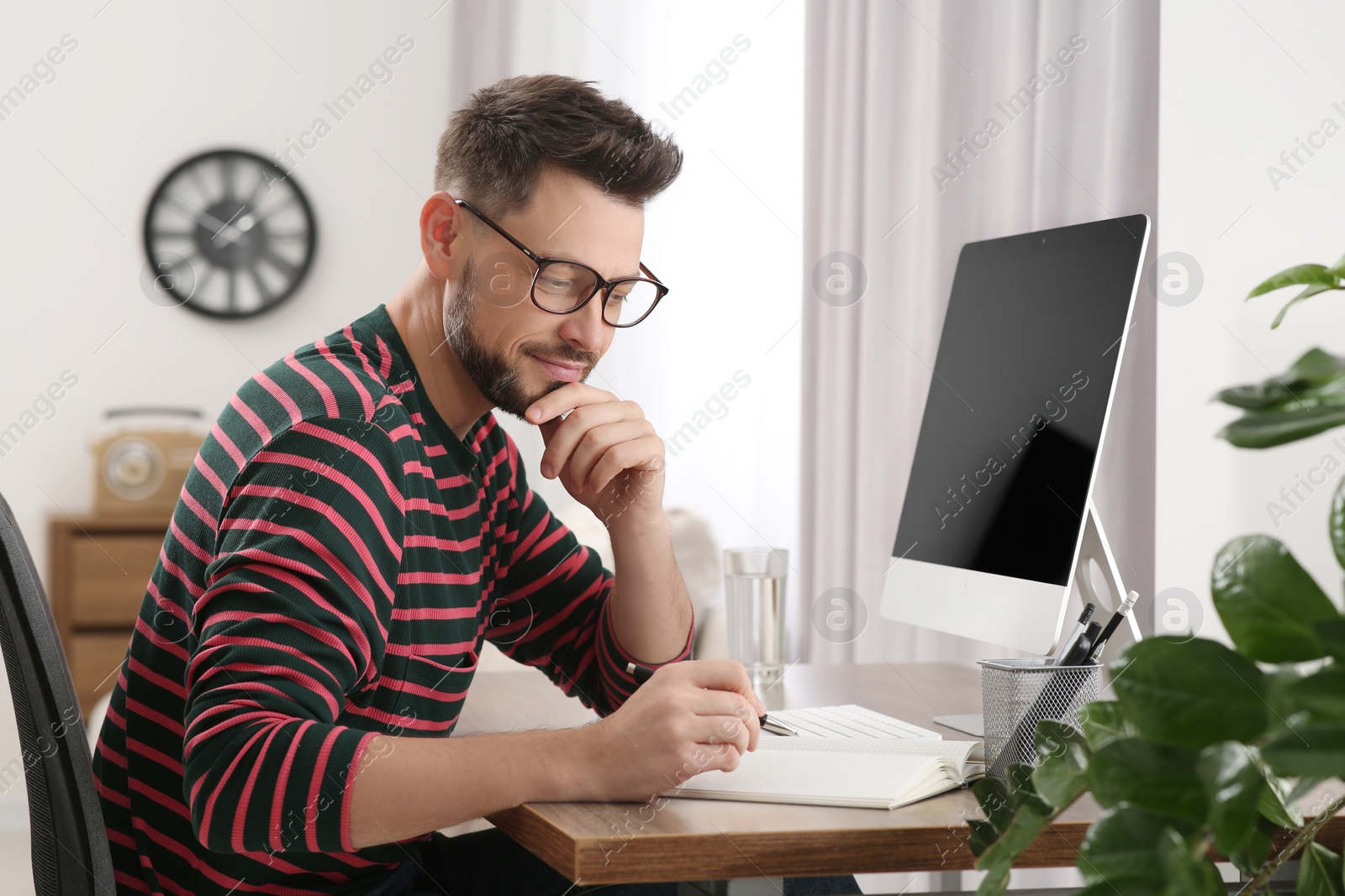 Photo of Man studying near computer at home. Online translation course