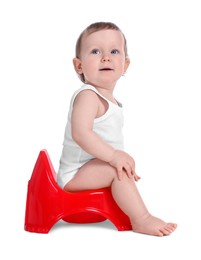 Little child sitting on baby potty against white background