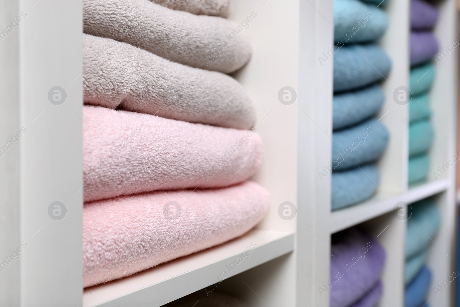 Photo of Colorful towels on shelves, closeup. Bathroom supplies