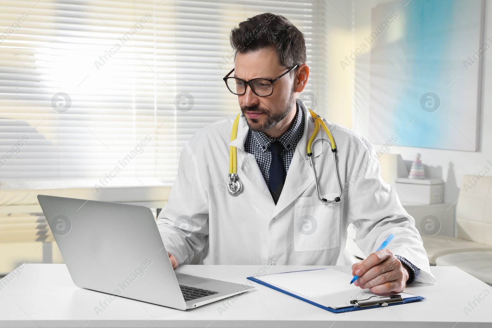 Photo of Pediatrician consulting patient online at table in clinic