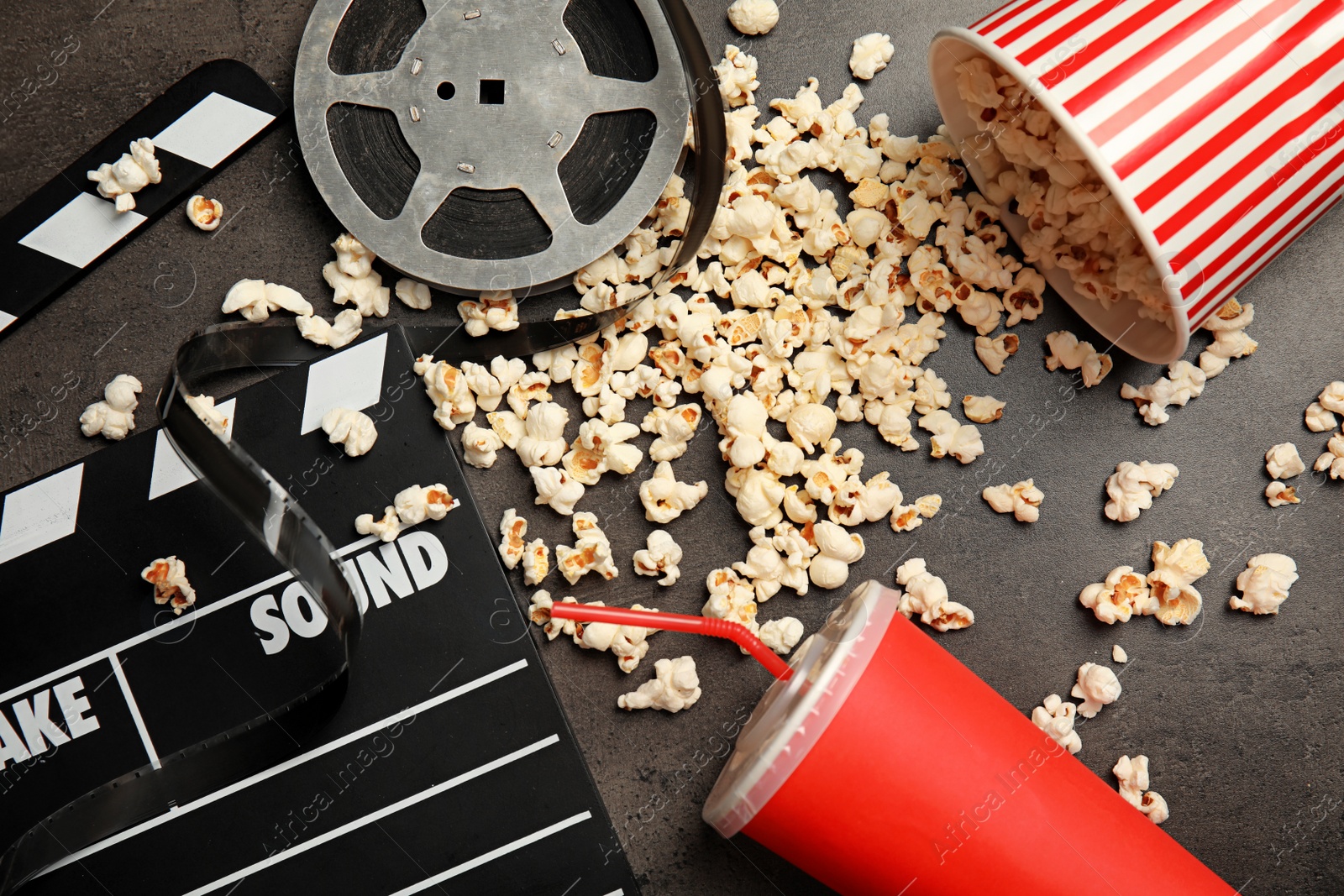 Photo of Flat lay composition with popcorn, film reel and clapperboard on grey background