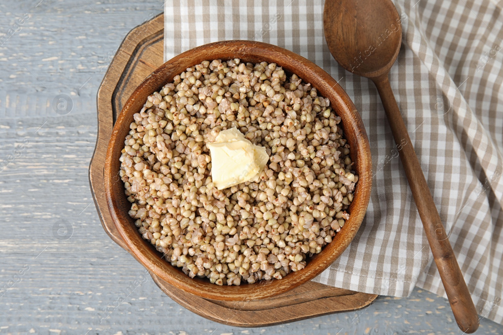 Photo of Tasty buckwheat porridge with butter on grey wooden table, flat lay