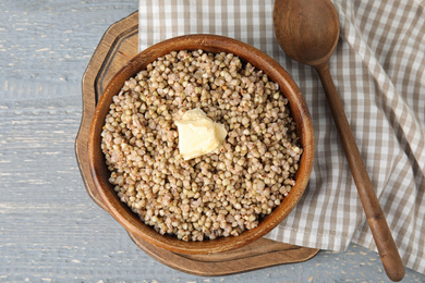 Photo of Tasty buckwheat porridge with butter on grey wooden table, flat lay