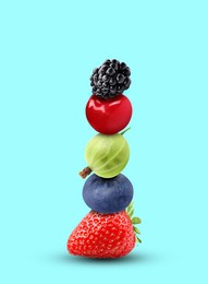 Stack of different fresh tasty berries and cherry on cyan background