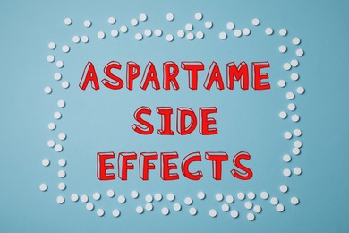 Image of Aspartame side effects. Sugar substitute tablets framing text on light blue background, top view