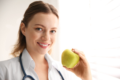 Photo of Nutritionist with apple near window in office