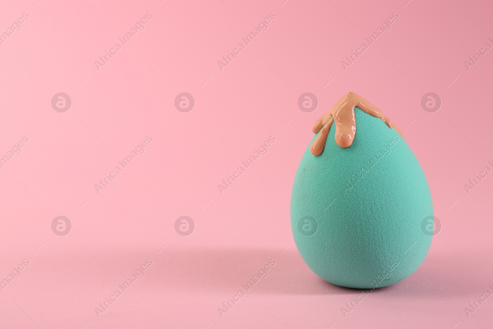 Photo of Makeup sponge with skin foundation on pink background. Space for text