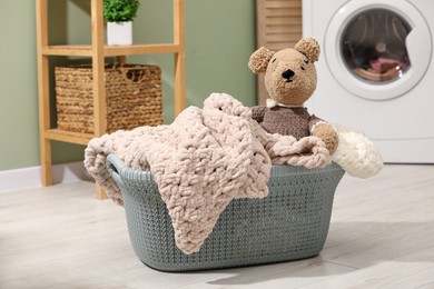 Photo of Laundry basket with soft blankets and toy in bathroom