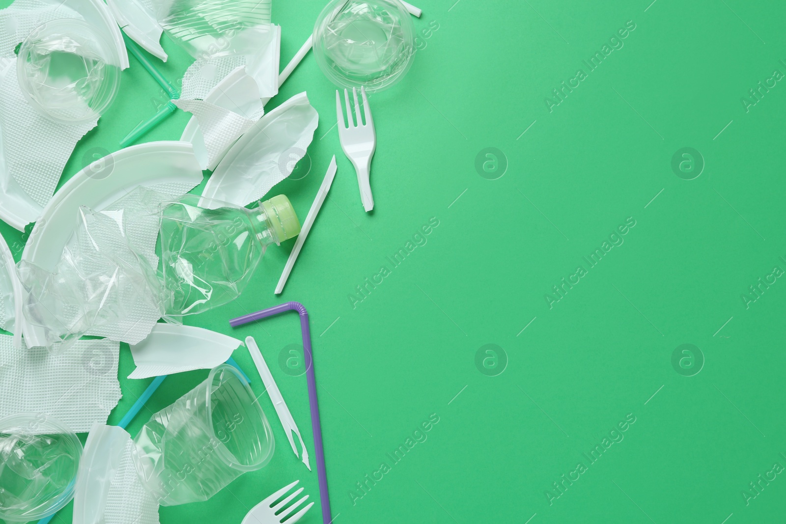Photo of Pile of different plastic items on green background, flat lay. Space for text