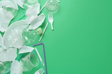 Pile of different plastic items on green background, flat lay. Space for text
