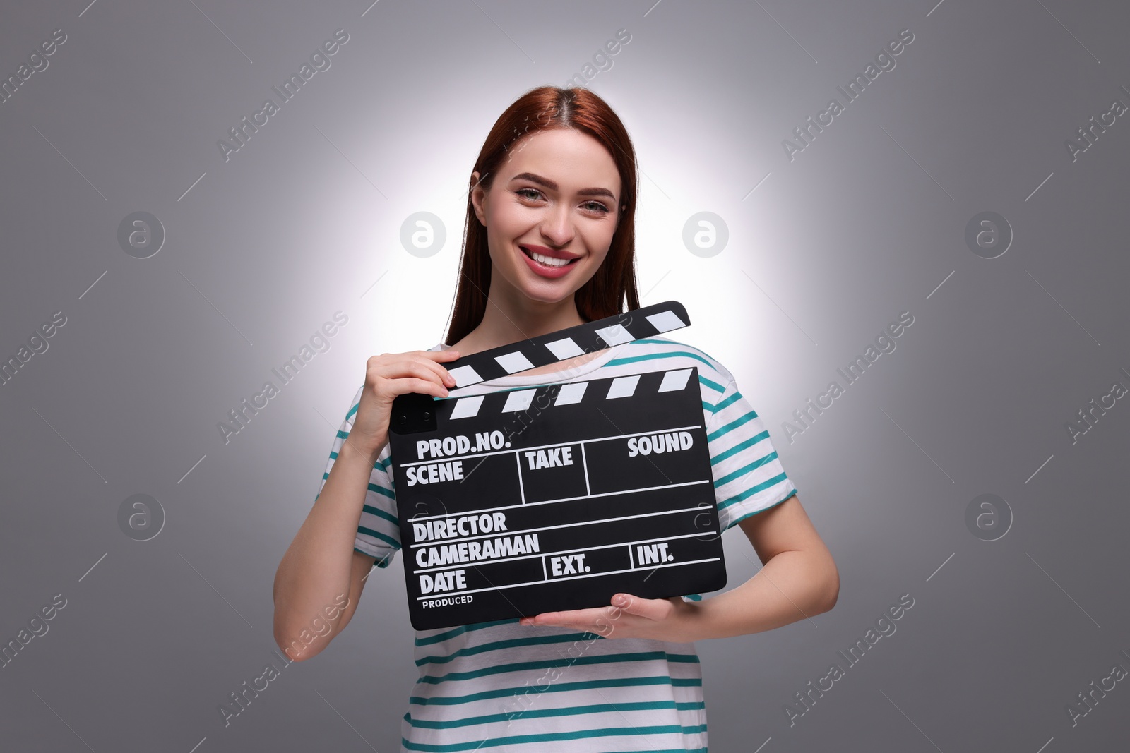 Photo of Happy actress with clapperboard on grey background. Film industry