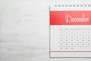 Photo of December calendar on white wooden background, top view. Space for text