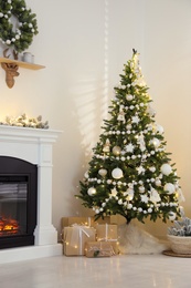 Decorated Christmas tree with faux fur skirt and gift boxes near fireplace indoors