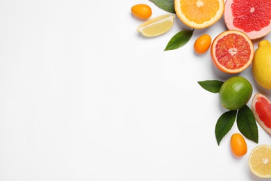 Photo of Fresh juicy citrus fruits with green leaves on light background, flat lay. Space for text