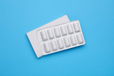 Photo of Blister with chewing gums on light blue background, top view